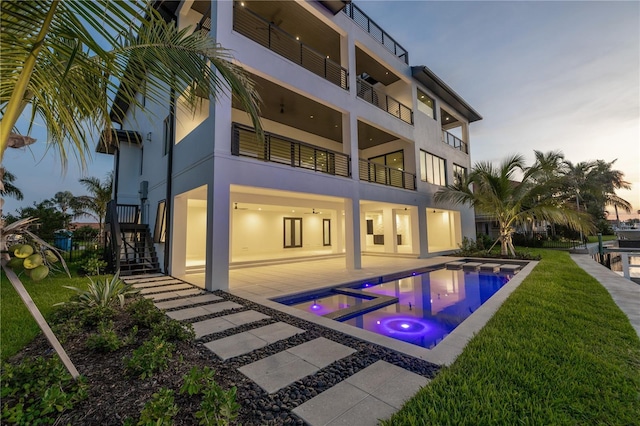 pool at dusk featuring an in ground hot tub and a patio area