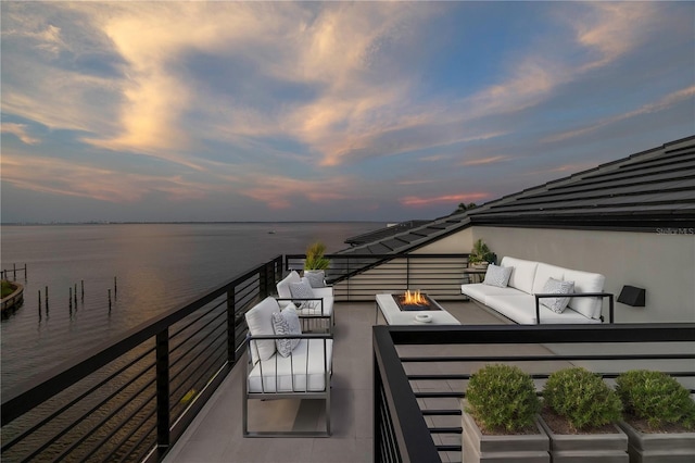 balcony at dusk with a water view and an outdoor living space with a fire pit