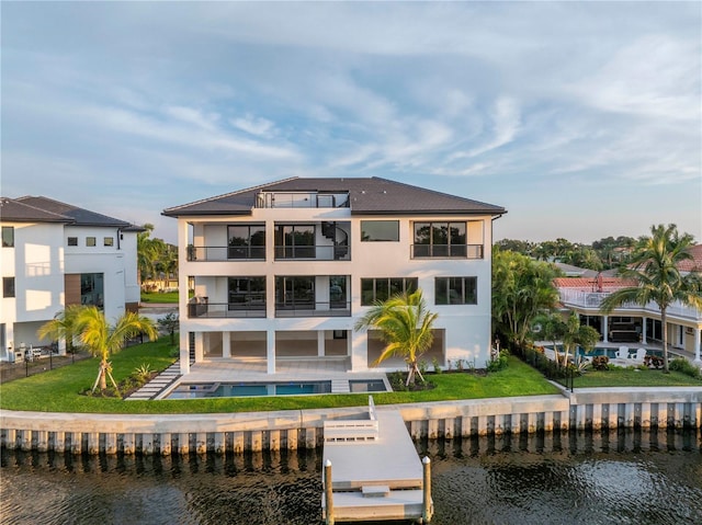 back of property with a water view, a balcony, and a pool