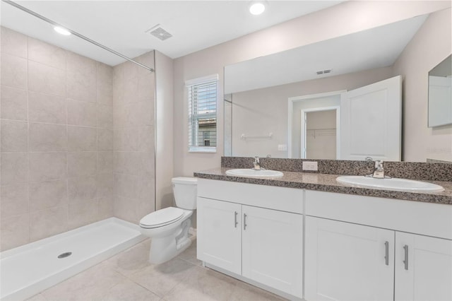 bathroom with tiled shower, vanity, toilet, and tile patterned floors