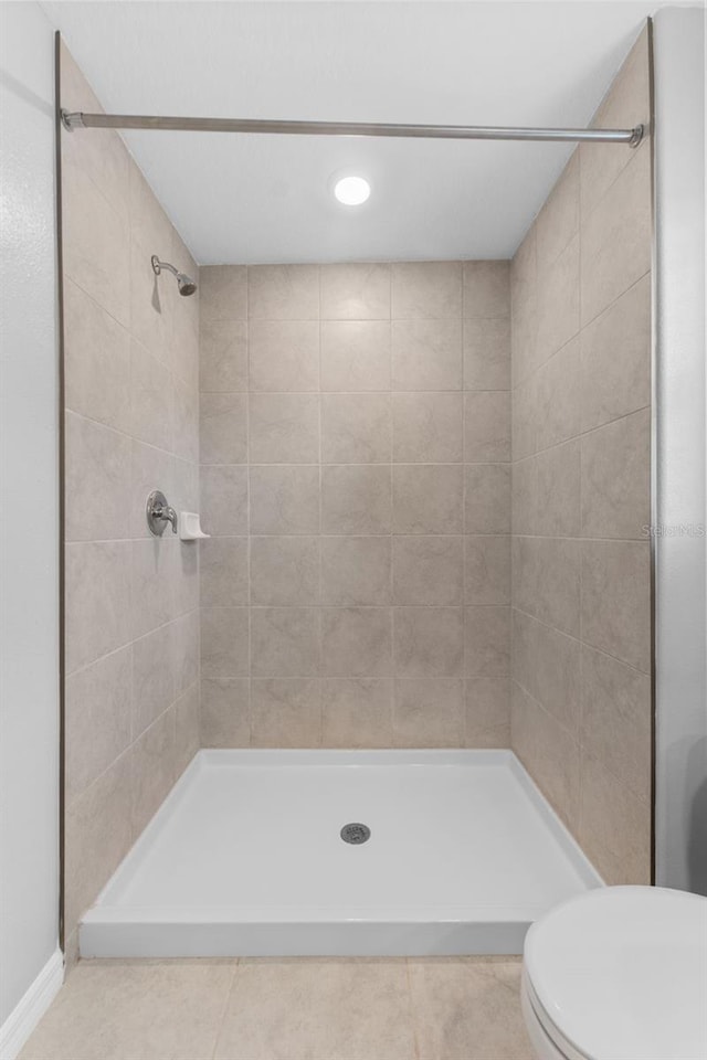 bathroom with tile patterned flooring, toilet, and tiled shower