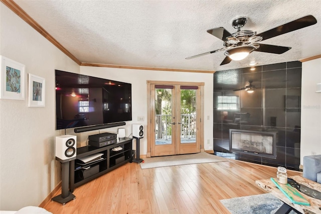 living room with wood-type flooring, a textured ceiling, crown molding, and french doors