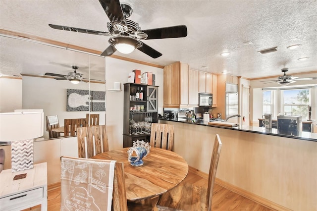 dining space with ornamental molding, light hardwood / wood-style floors, and a textured ceiling