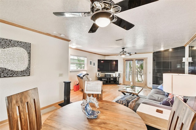 dining space featuring french doors, ornamental molding, light hardwood / wood-style floors, and a wealth of natural light