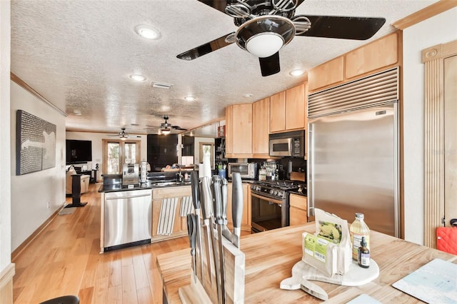 kitchen featuring appliances with stainless steel finishes, light brown cabinetry, light hardwood / wood-style floors, crown molding, and a textured ceiling