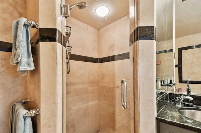 bathroom with vanity, an enclosed shower, and a textured ceiling