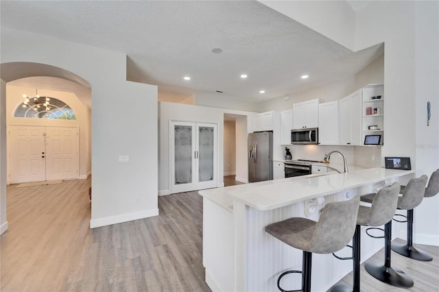 kitchen featuring white cabinetry, light hardwood / wood-style floors, french doors, and appliances with stainless steel finishes