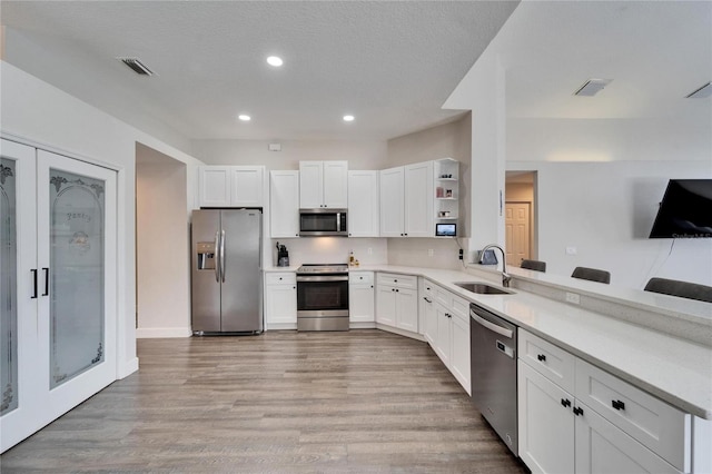 kitchen with sink, stainless steel appliances, light hardwood / wood-style floors, and white cabinets