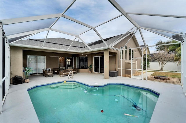 view of swimming pool with a lanai, a patio area, and an outdoor living space with a fire pit