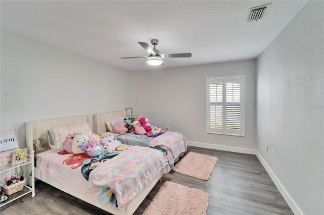 bedroom featuring ceiling fan, dark hardwood / wood-style floors, and a textured ceiling