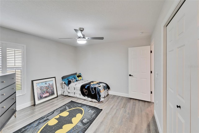 bedroom with hardwood / wood-style flooring, ceiling fan, and a textured ceiling