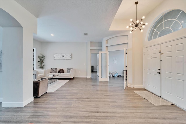 entryway with an inviting chandelier, light hardwood / wood-style floors, and a textured ceiling