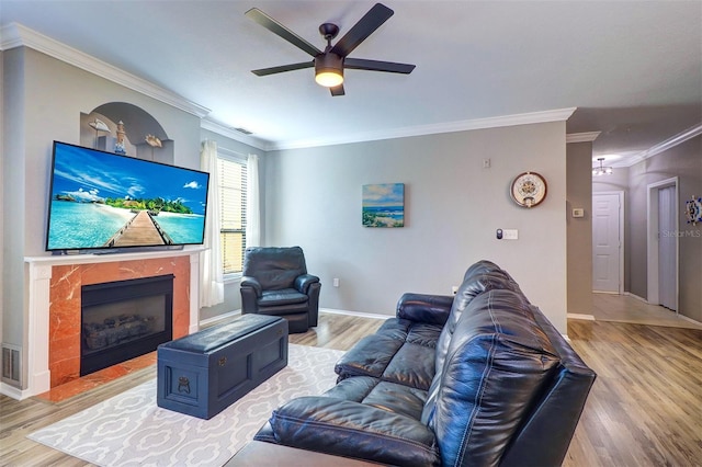 living room featuring ceiling fan, ornamental molding, a premium fireplace, and light hardwood / wood-style floors