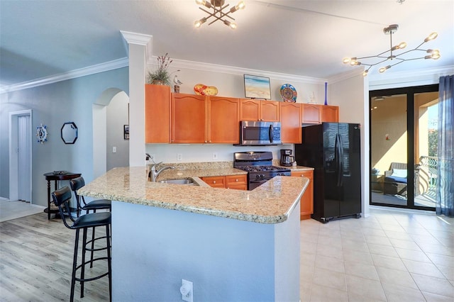 kitchen featuring black fridge with ice dispenser, sink, gas stove, decorative light fixtures, and kitchen peninsula