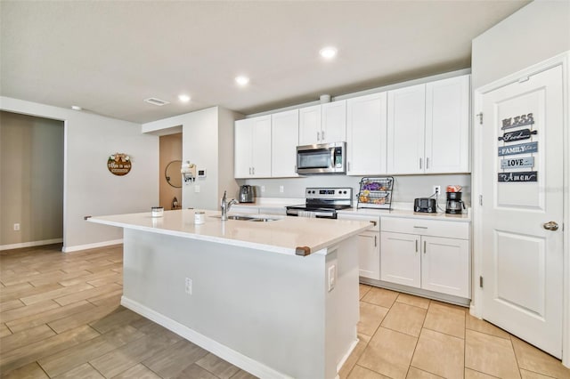 kitchen with appliances with stainless steel finishes, sink, a center island with sink, and white cabinets