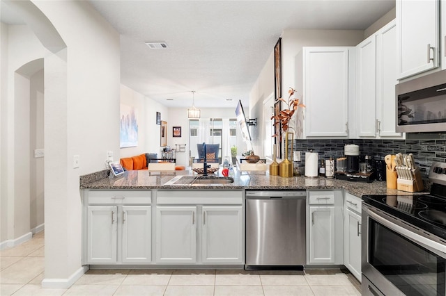 kitchen with stainless steel appliances, dark stone counters, and white cabinets