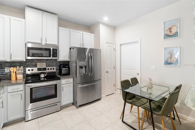 kitchen with tasteful backsplash, appliances with stainless steel finishes, white cabinets, and dark stone counters