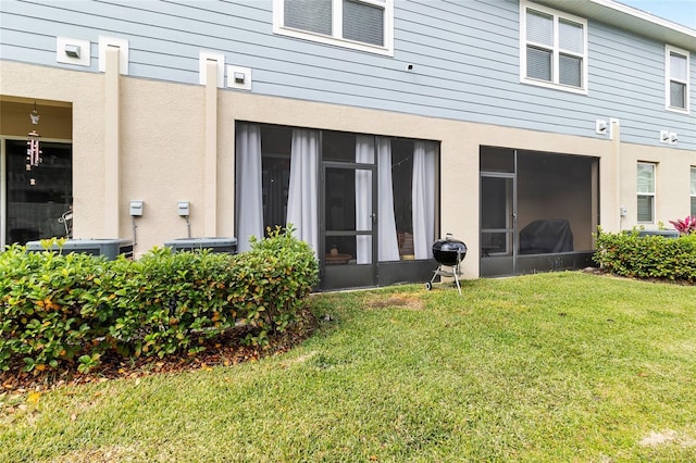 back of house featuring a sunroom and a lawn