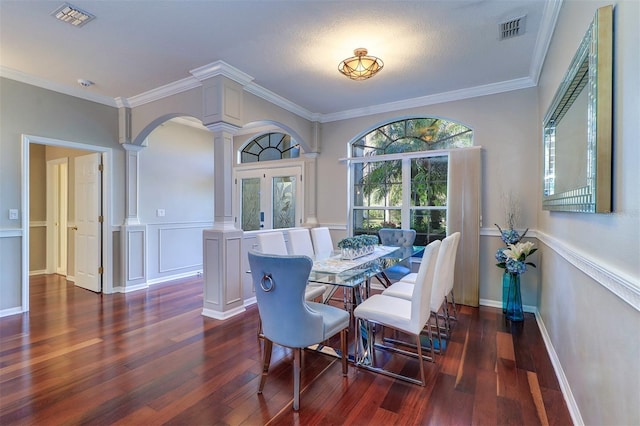 dining room featuring dark hardwood / wood-style flooring, ornamental molding, and decorative columns