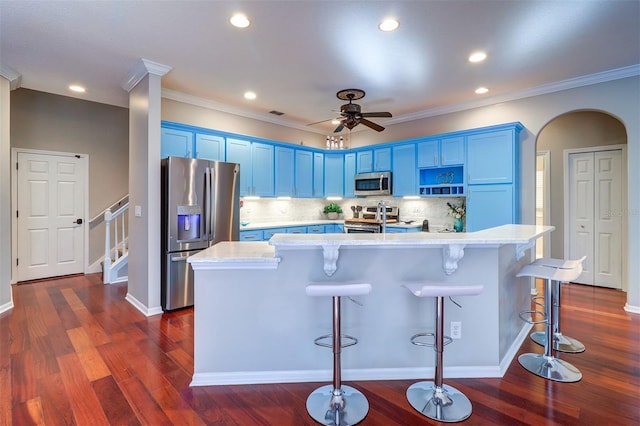 kitchen with blue cabinetry, a kitchen bar, dark hardwood / wood-style floors, an island with sink, and stainless steel appliances