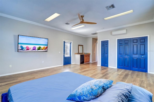 bedroom with multiple closets, a wall mounted AC, and hardwood / wood-style floors