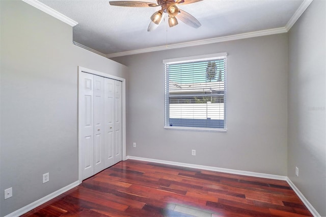 unfurnished bedroom featuring dark wood-type flooring, ceiling fan, crown molding, and a closet