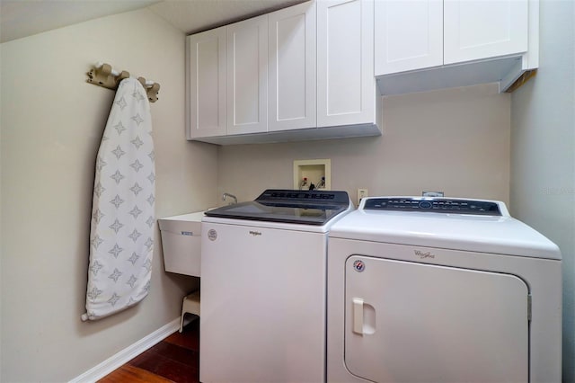 clothes washing area with cabinets, washer and dryer, sink, and dark hardwood / wood-style flooring