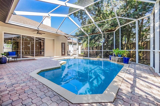 view of swimming pool with ceiling fan, a lanai, and a patio