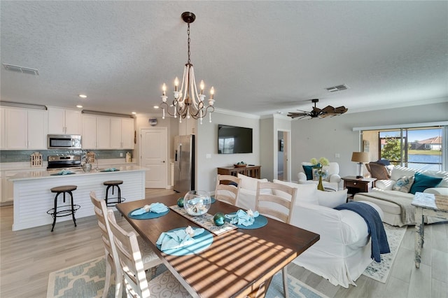 dining space with ceiling fan with notable chandelier, light wood-type flooring, crown molding, and a textured ceiling