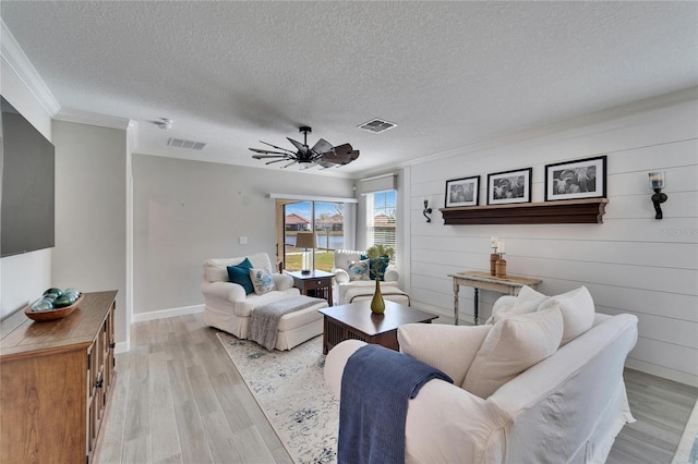 living room featuring light hardwood / wood-style floors, a textured ceiling, ceiling fan, and ornamental molding