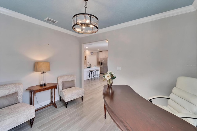 sitting room featuring sink, crown molding, an inviting chandelier, and light hardwood / wood-style flooring