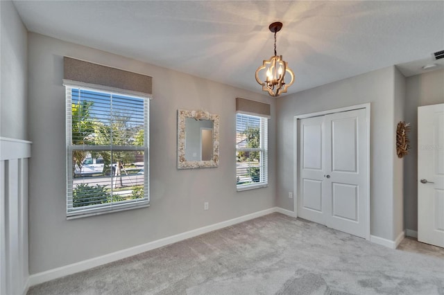 unfurnished bedroom featuring light carpet, a chandelier, and a closet