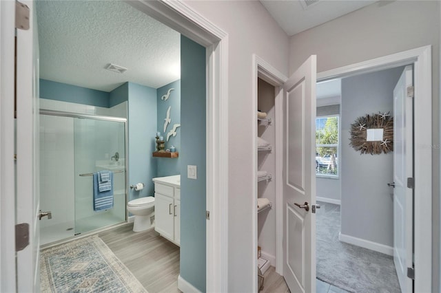 bathroom with toilet, a textured ceiling, an enclosed shower, and vanity