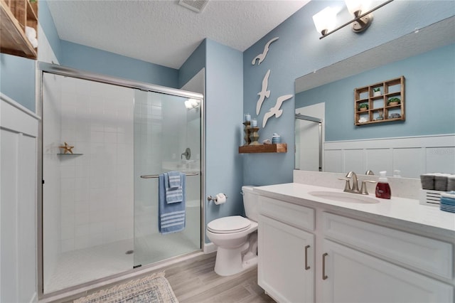 bathroom with hardwood / wood-style flooring, toilet, a textured ceiling, an enclosed shower, and vanity