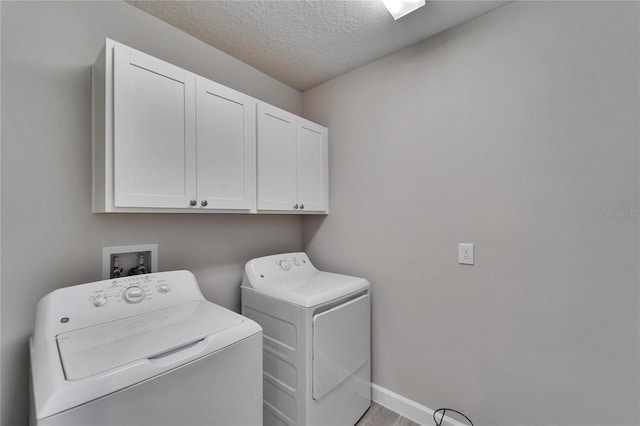 laundry area with separate washer and dryer, cabinets, and a textured ceiling