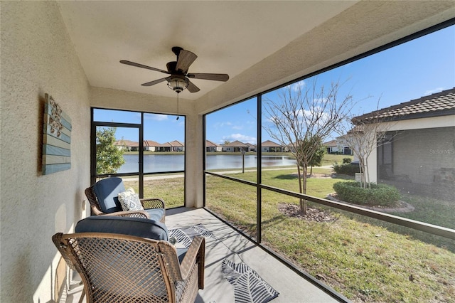 sunroom / solarium with ceiling fan and a water view