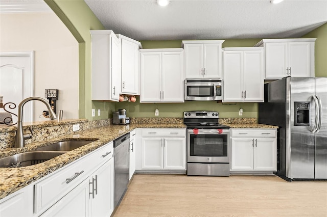 kitchen with stainless steel appliances, white cabinetry, and sink