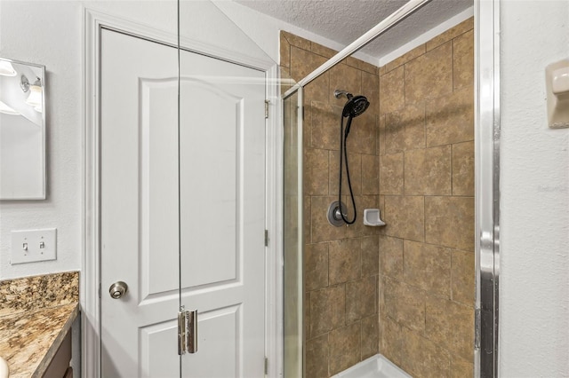 bathroom with walk in shower, vanity, and a textured ceiling