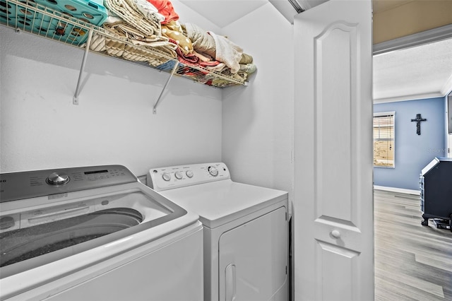 clothes washing area with washing machine and clothes dryer and light hardwood / wood-style floors