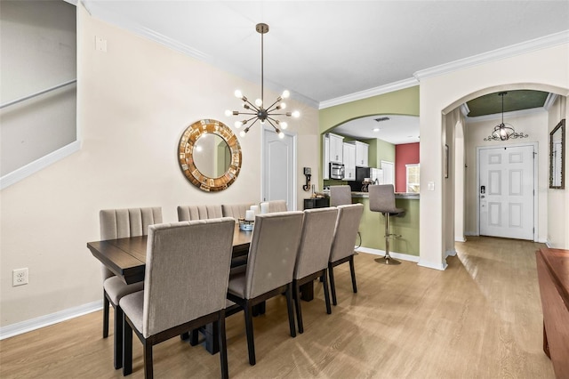 dining space with ornamental molding, a chandelier, and light wood-type flooring