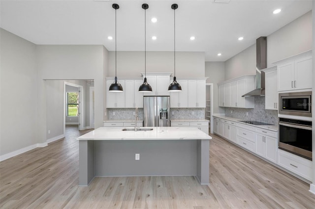 kitchen with white cabinetry, hanging light fixtures, wall chimney exhaust hood, and appliances with stainless steel finishes