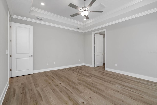 spare room featuring ceiling fan, ornamental molding, a raised ceiling, and light wood-type flooring