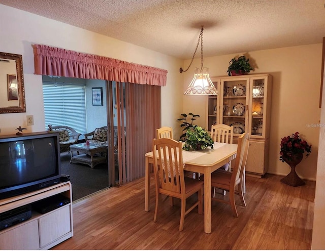 dining room featuring wood-type flooring and a textured ceiling