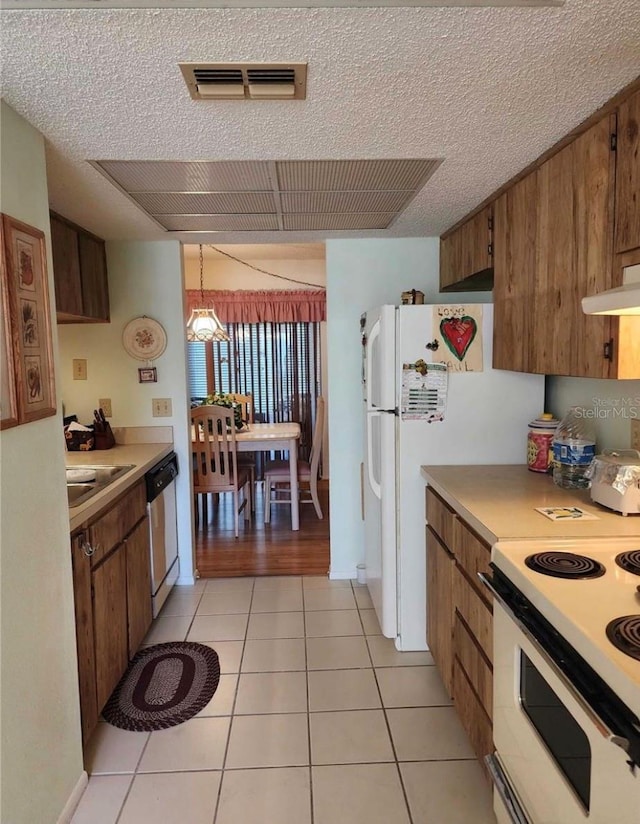 kitchen featuring light tile patterned flooring, pendant lighting, a textured ceiling, and white appliances