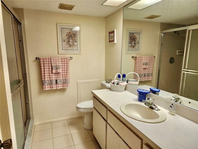 bathroom featuring a shower with shower door, vanity, toilet, tile patterned floors, and a textured ceiling