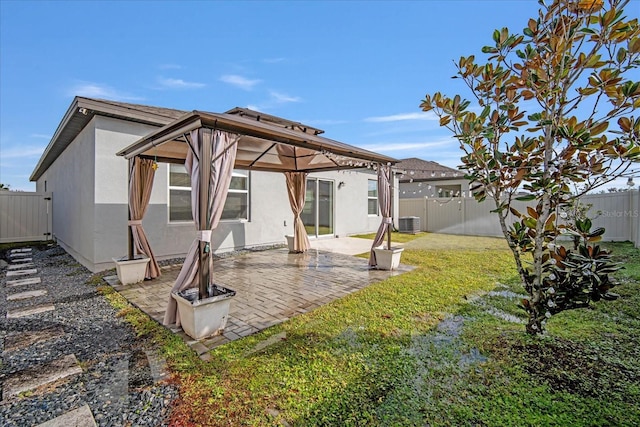 back of house featuring cooling unit, a gazebo, a lawn, and a patio