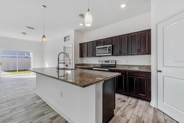 kitchen with pendant lighting, an island with sink, appliances with stainless steel finishes, and sink