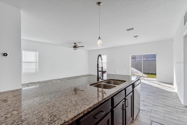 kitchen with light stone countertops, sink, a wealth of natural light, and decorative light fixtures