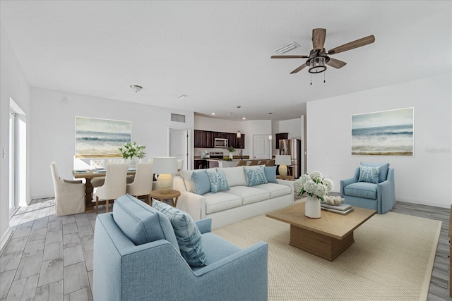 living room with ceiling fan and light wood-type flooring