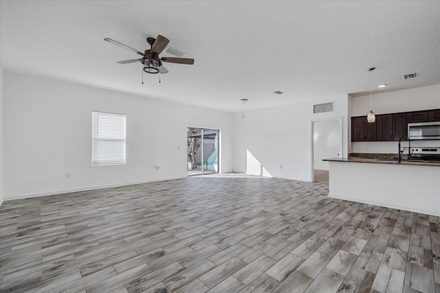 unfurnished living room featuring sink, light hardwood / wood-style flooring, and ceiling fan